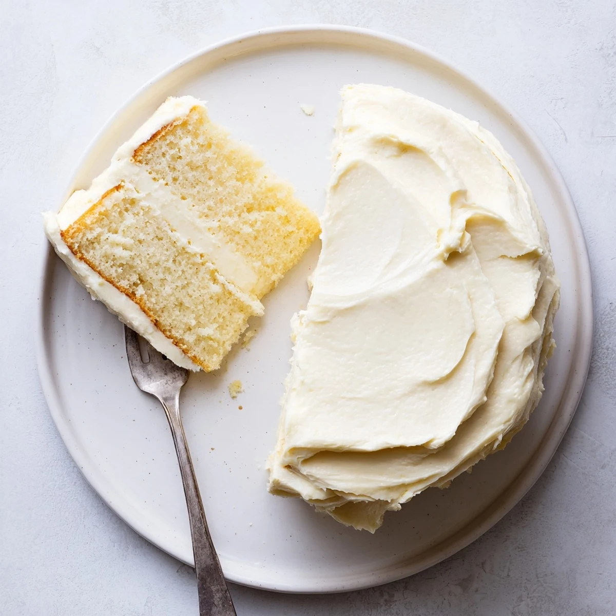 Classic perfect vanilla cake served on a pedestal stand with thick swirled buttercream frosting and festive sprinkles