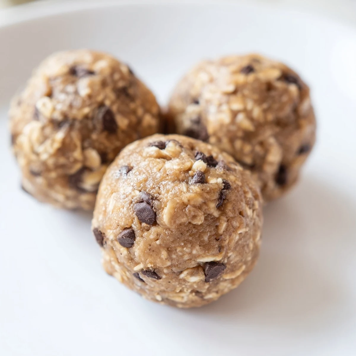 Close-up of protein-packed no-bake energy balls dotted with dark chocolate chips and fresh mint green coloring