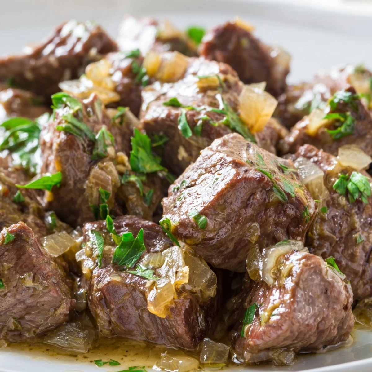 Savory steak bites bubbling in buttery sauce with chopped onions ready for weeknight dinner serving