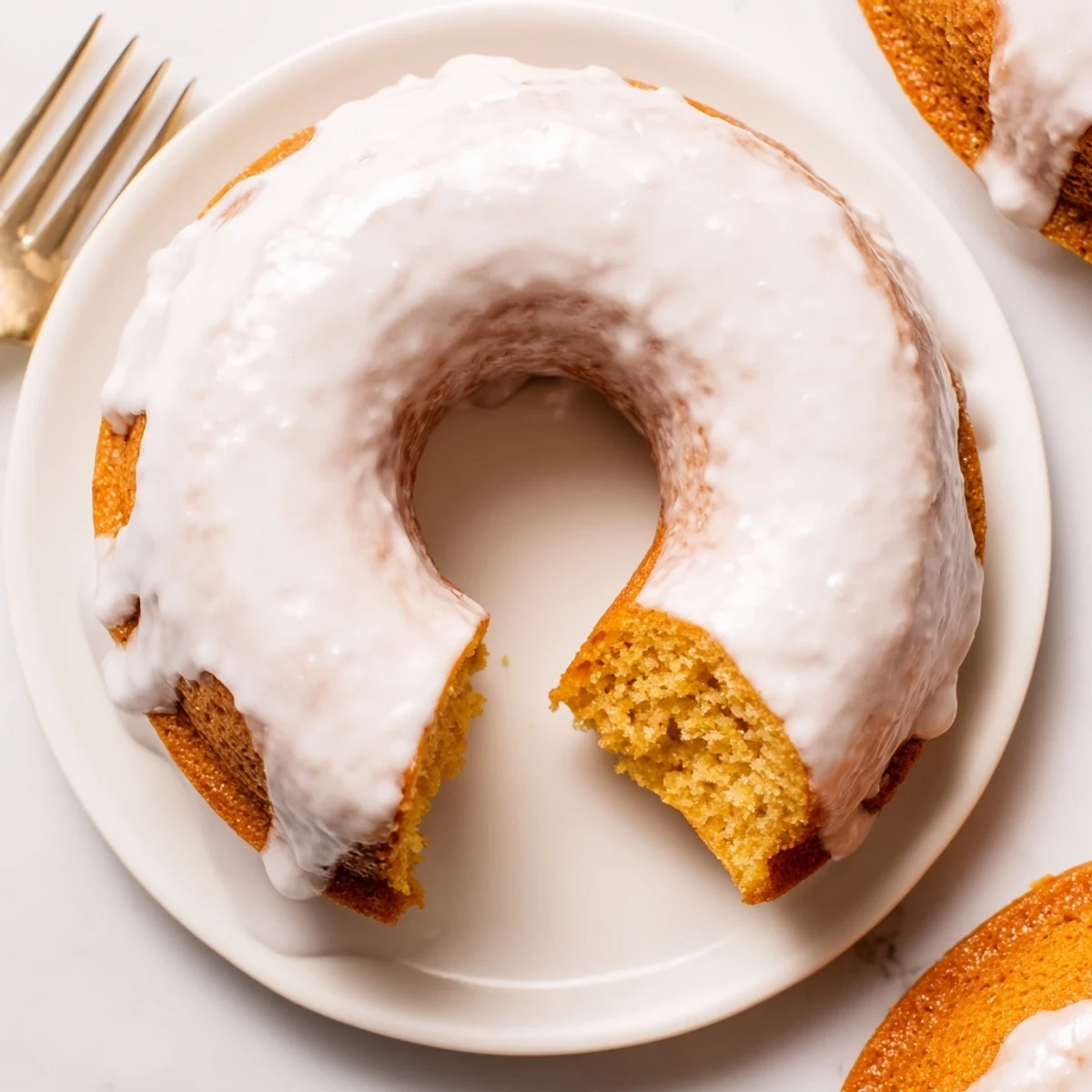 Golden baked Greek yogurt cake donuts topped with sweet vanilla glaze and colorful sprinkles on a white plate