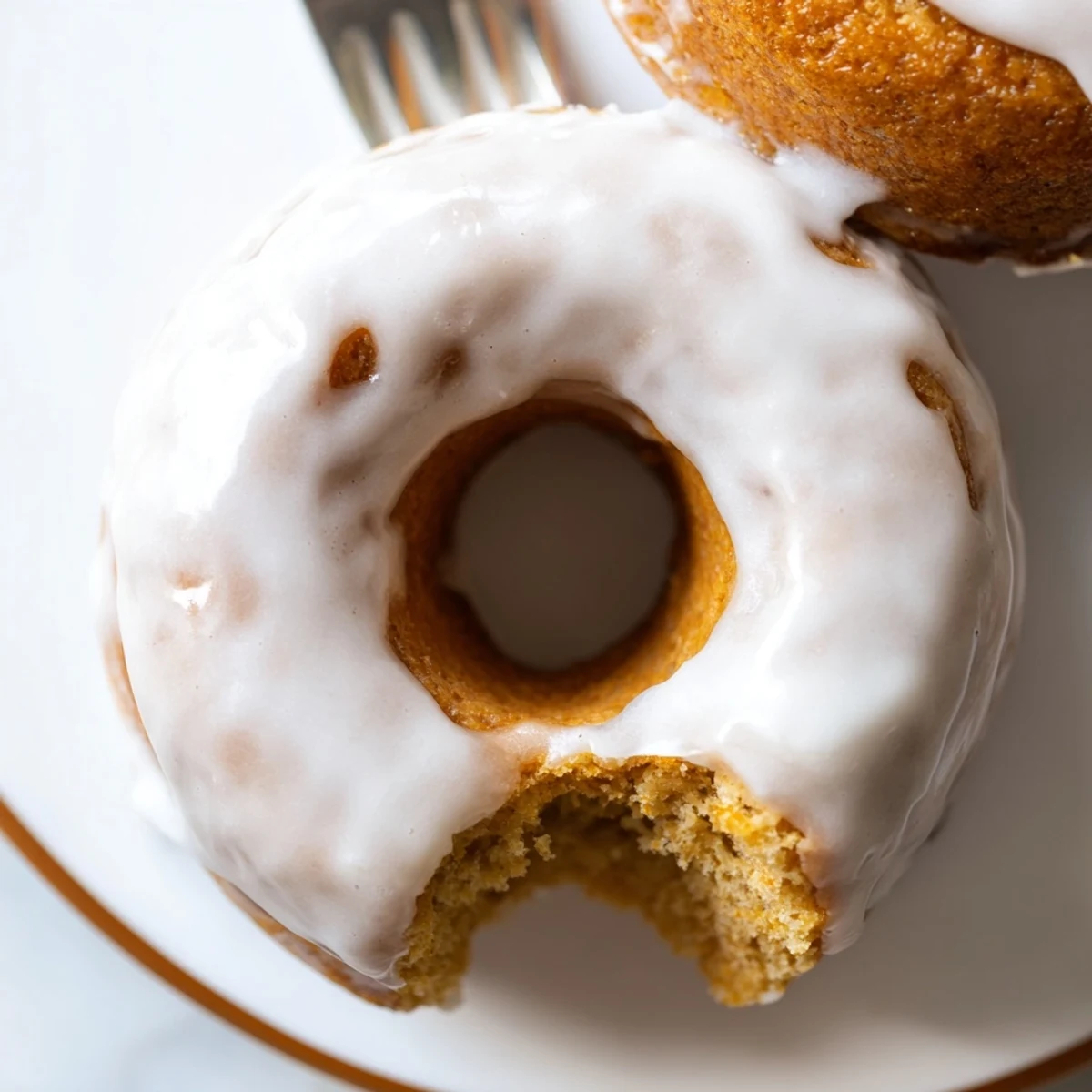 Batch of twelve golden brown Greek yogurt cake donuts arranged on a wire cooling rack with white glaze dripping down the sides