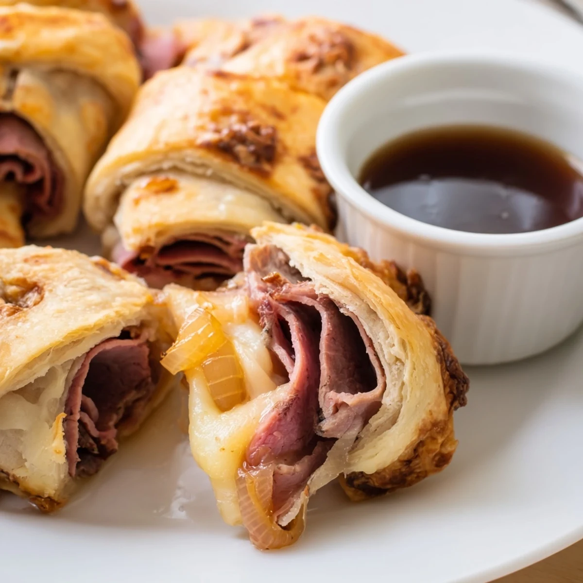 Crescent-wrapped beef and cheese French dip roll ups with melted provolone and caramelized onion filling