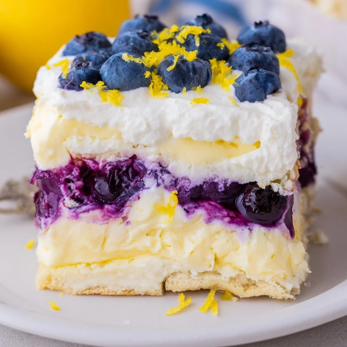 A chilled lemon blueberry lasagna dessert garnished with fresh berries and zest