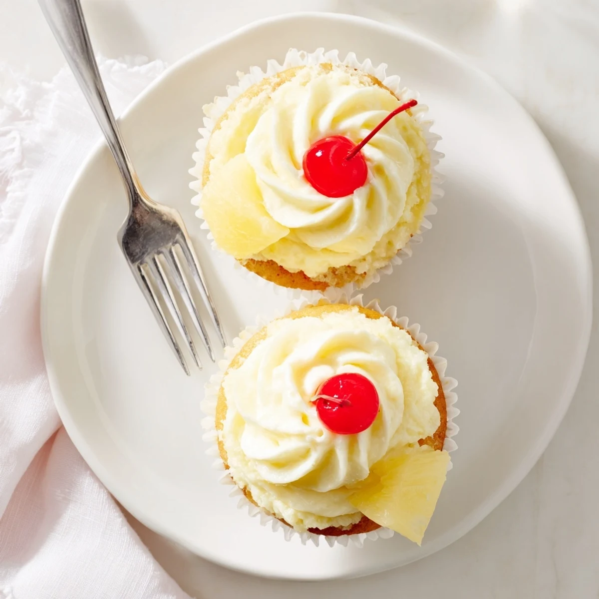 Golden Dole Whip Cupcakes topped with fluffy pineapple whipped frosting and a cherry