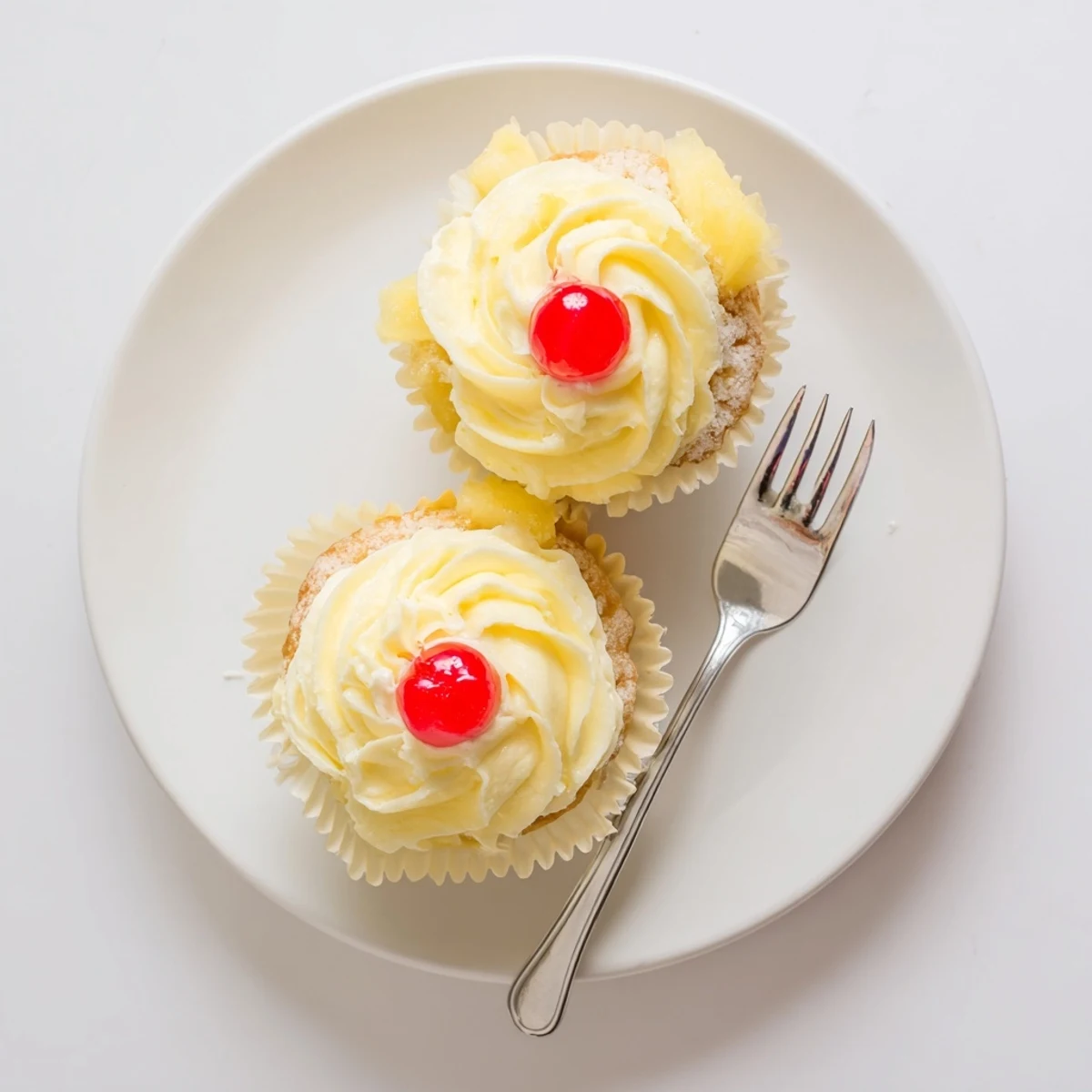 Moist pineapple Dole Whip Cupcakes piped with creamy yellow frosting on a white plate