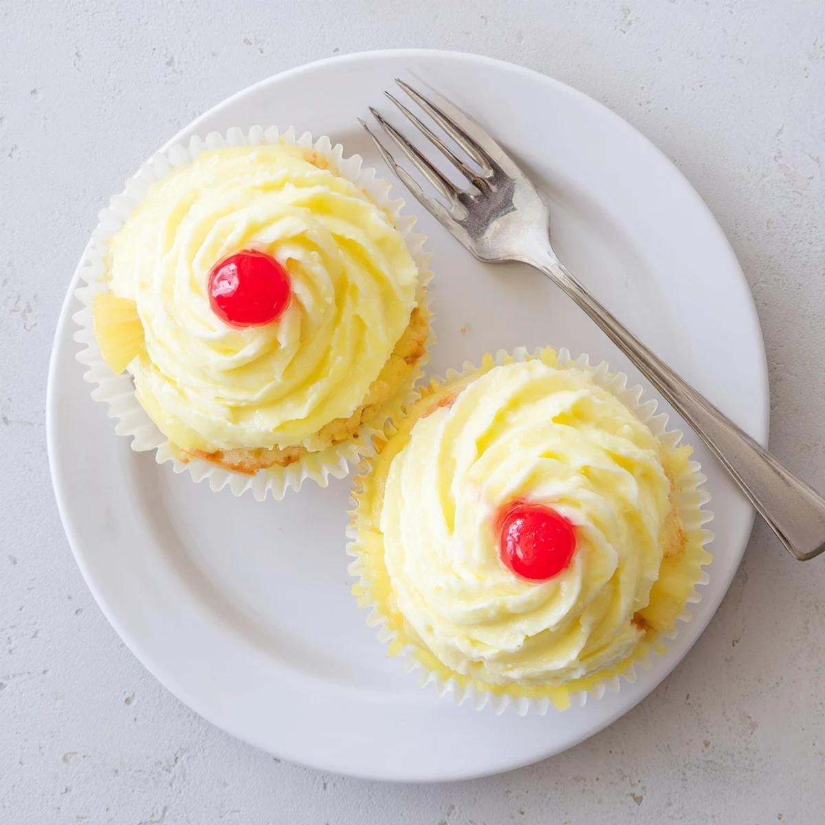 A batch of Dole Whip Cupcakes garnished with fresh pineapple wedges on a baking sheet