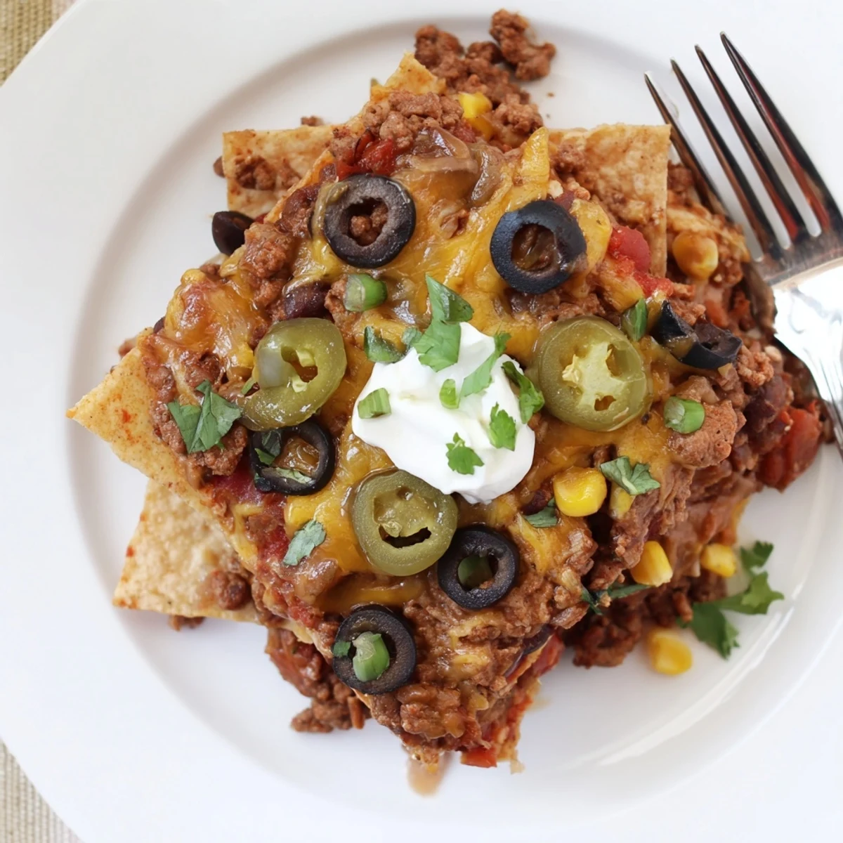 Family-style Cheesy Nacho Casserole layered with seasoned beef, topped with cilantro