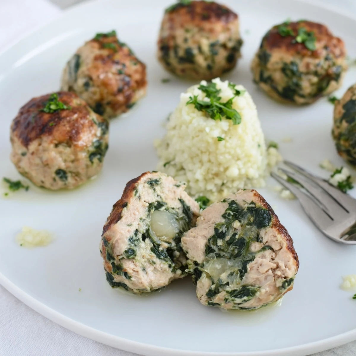 Fork-tender Low Carb Spinach Chicken Meatballs served over cauliflower rice, fresh basil