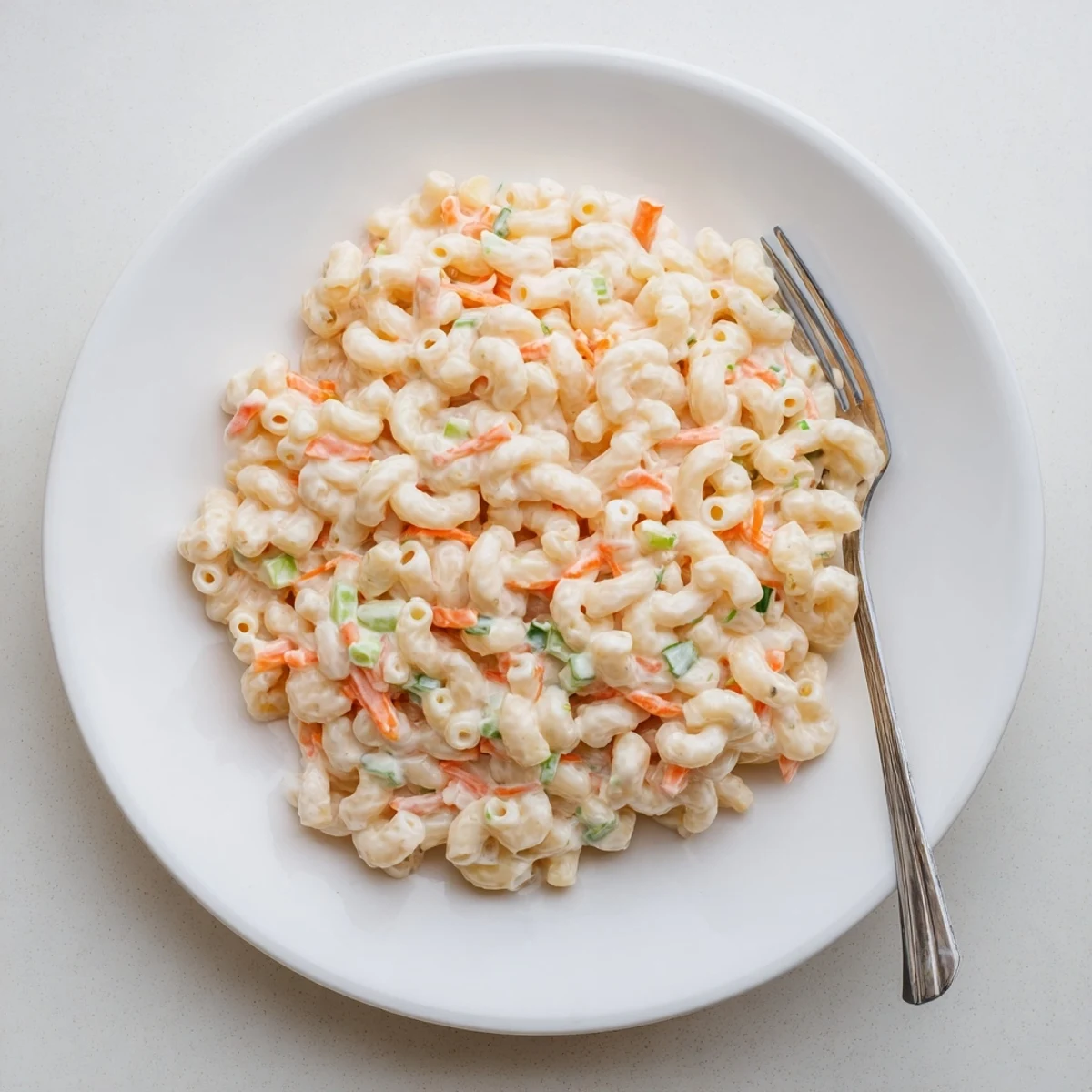 Golden macaroni coated in tangy mayonnaise dressing mixed with grated carrots and celery for this classic Hawaiian style mac salad
