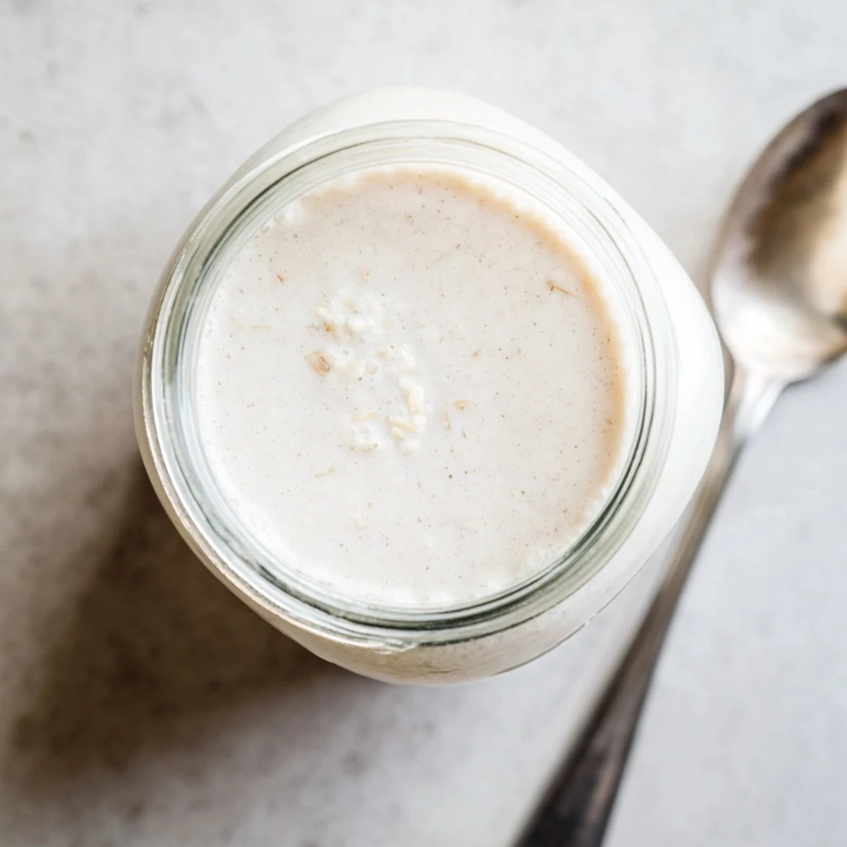 Glass jar filled with creamy homemade almond milk garnished with cinnamon stick