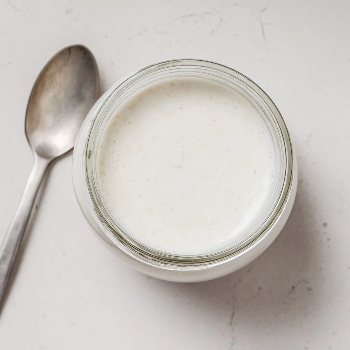 White bowl of soaked raw almonds beside blender making creamy vegan almond milk