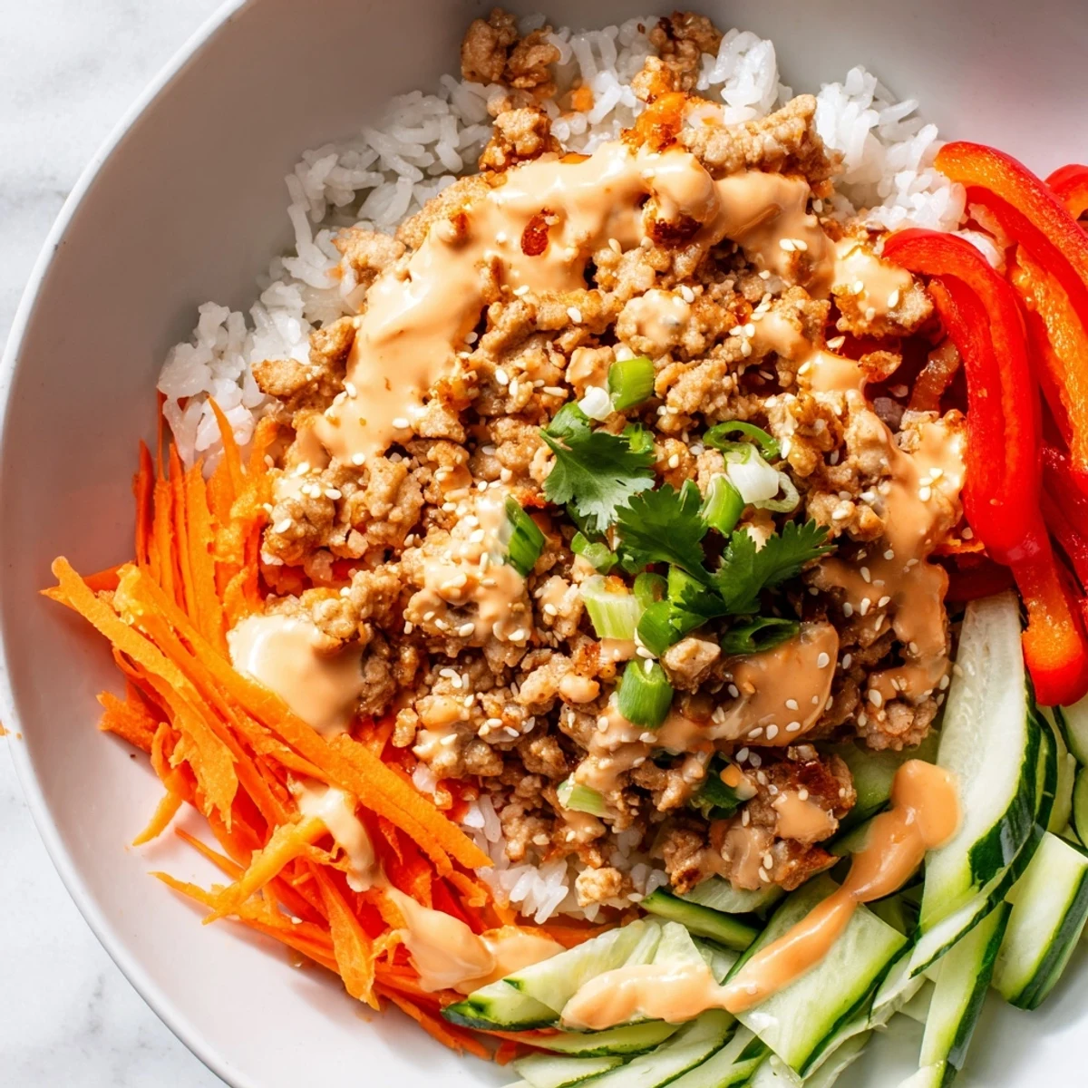 Bowls of caramelize ground turkey topped with Bang Bang sauce sesame seeds and fresh herbs